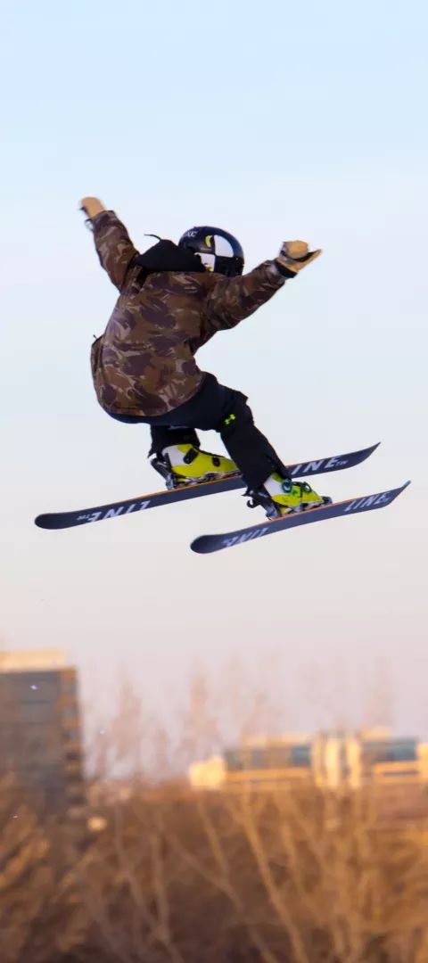 Skier jumping with buildings behind at Hyland Hills