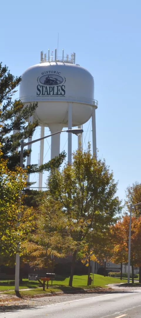 Road with water tower, church steeple and fall trees