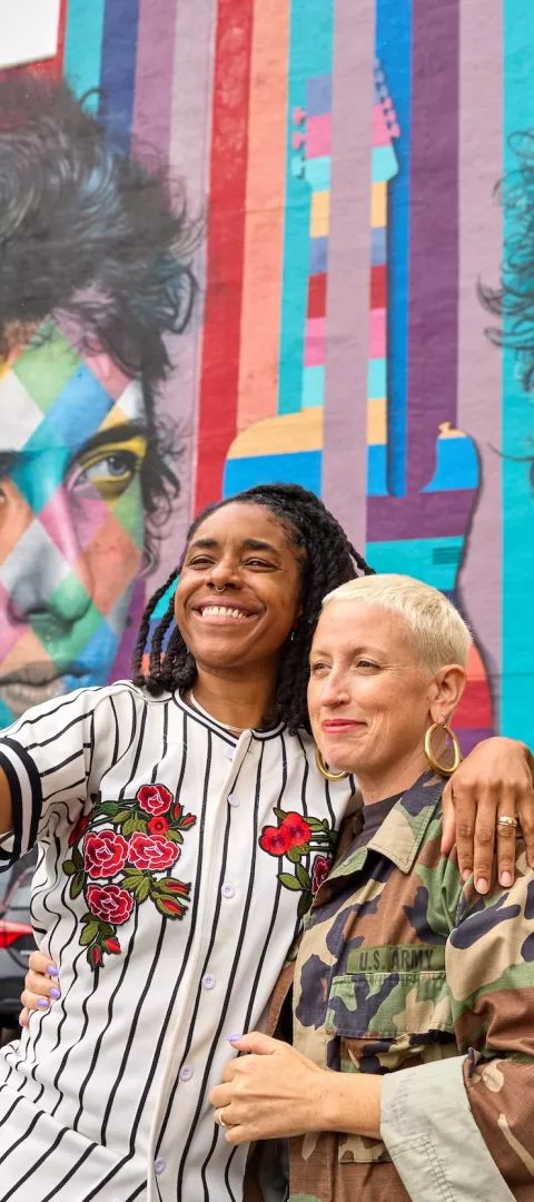 A couple takes their picture in front of the Bob Dylan mural in downtown Minneapolis